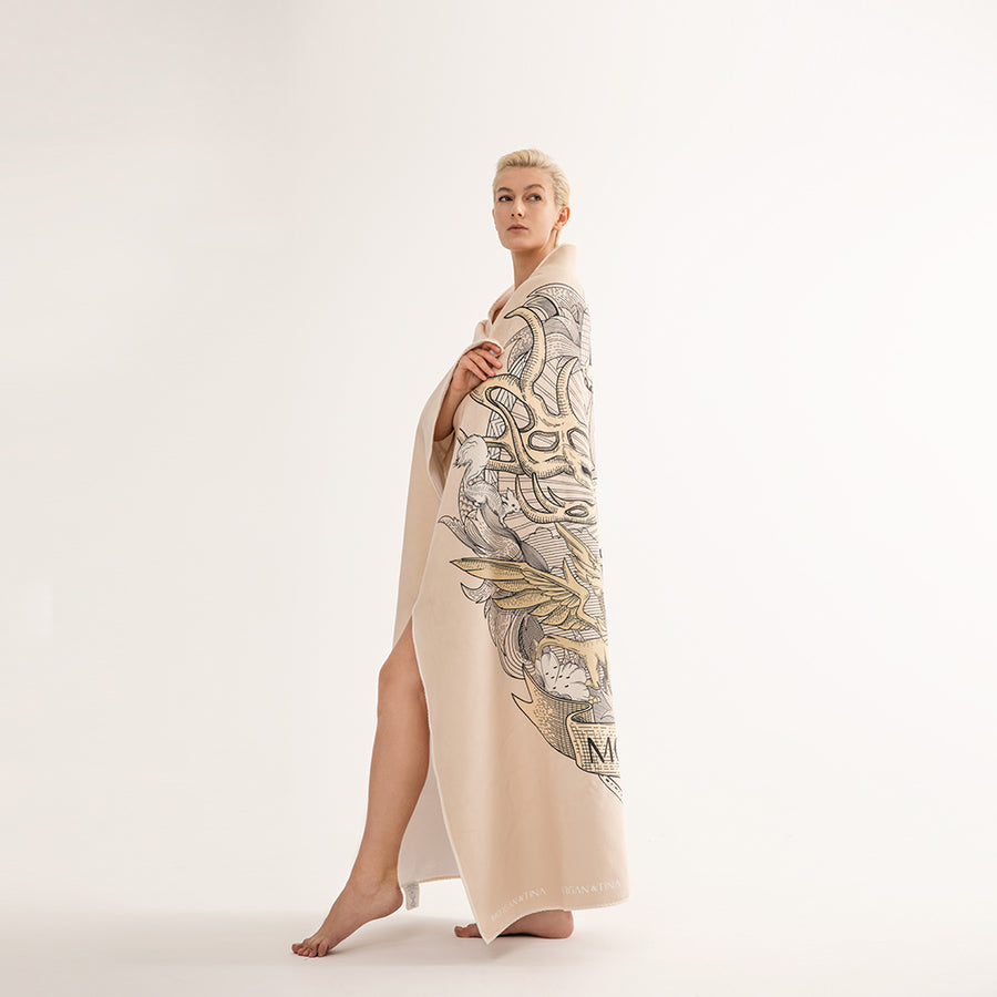 A beautiful woman wearing a Morgan&Tina beige personalized bath towel with a stag of the Yggdrasil on it.